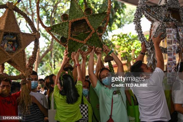 Teachers, students and parents hold Christmas lanterns made from recycled materials during a campaign for a toxic-free and waste-free Christmas...