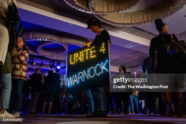 December 6, 2022: A supporters carries a sign in support of Senator Raphael Warnock during Warnock for Georgia run-off Election Night Watch Party at...