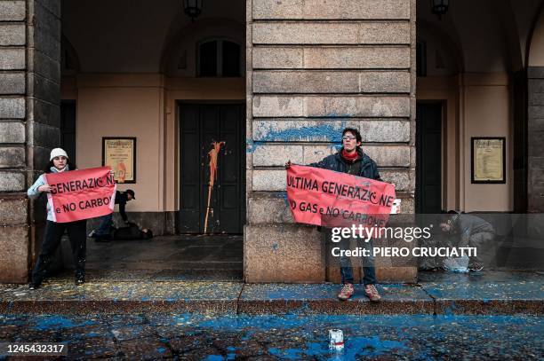 Environmental activists from the "Last Generation" group hold banners after they smeared with paint the facade of the La Scala theatre during a...