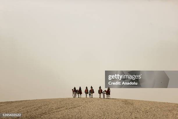 People ride camels during a desert safari in Doha, Qatar on December 5, 2022. For soccer fans traveling to Qatar for the 2022 FIFA World Cup, desert...