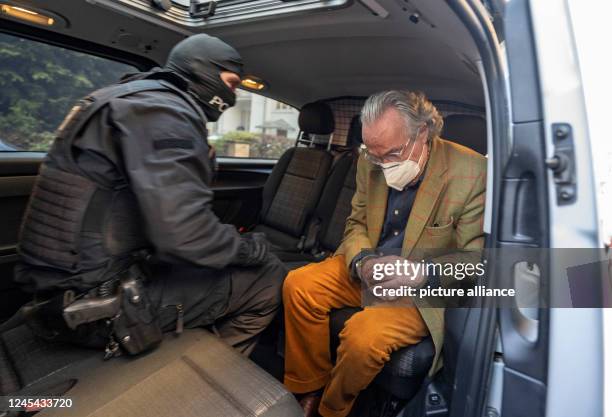 December 2022, Hessen, Frankfurt/Main: During a raid against so-called "Reich citizens", a hooded police officer sits in a police vehicle with the...