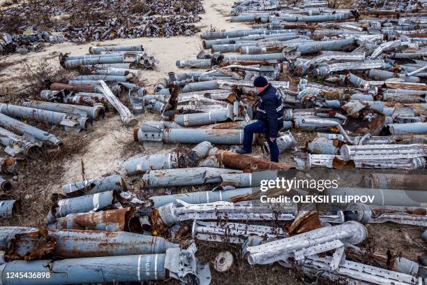 This aerial picture taken on December 7, 2022 shows an expert of the prosecutor's office examining collected remnants of shells and missiles used by...