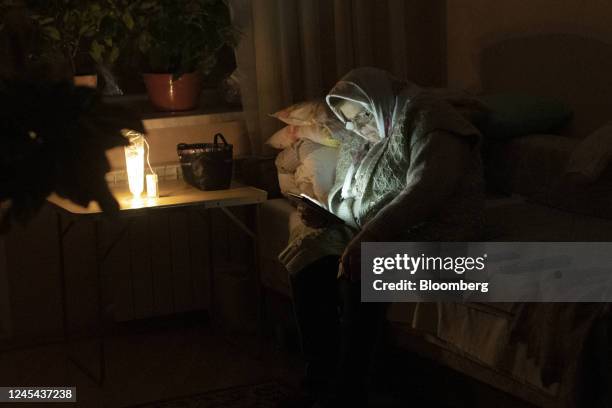 Resident uses a battery powered light to read at home during a power outage in Kyiv, Ukraine, on Tuesday, Dec. 6, 2022. Ukrainians have been no...