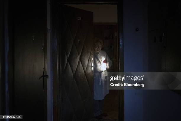Resident opens their apartment door with a battery powered light during a power outage in Kyiv, Ukraine, on Tuesday, Dec. 6, 2022. Ukrainians have...