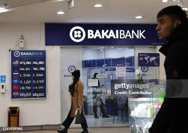 Woman walks by the exchange office of the Bakai bank as the rates of the Kyrgyzstani som ruble to the U.S. Dollar, ruble and the Euro seen at the...