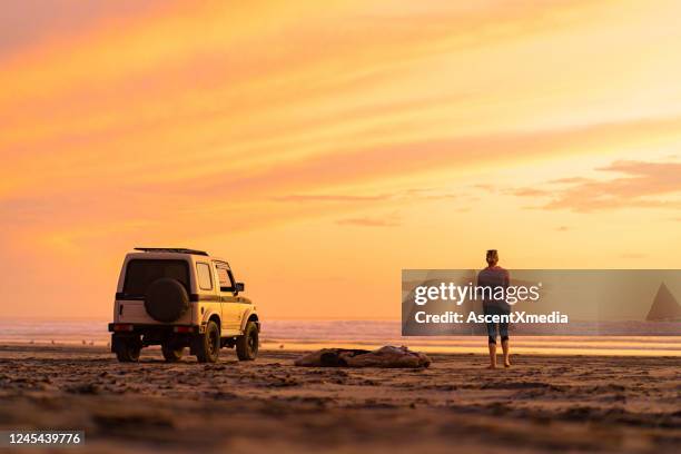 frau steigt aus dem auto, um am strand bei sonnenaufgang zu tanzen - voyage zen stock-fotos und bilder