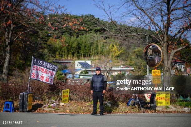 This photo taken on November 16 shows Ryu Guk-hyun posing next to flags and placards at his protest spot on the side of a road from where he has been...