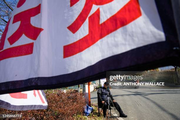This photo taken on November 16 shows proteser Ryu Guk-hyun posing next to flags and placards at his protest spot on the side of a road from where he...