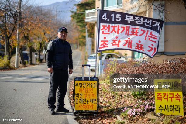 This photo taken on November 16 shows protester Ryu Guk-hyun posing next to flags and placards at his protest spot on the side of a road from where...