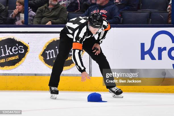 Referee Garrett Rank picks up a hat following a hat trick scored by Tage Thompson of the Buffalo Sabres during the first period of a game against the...