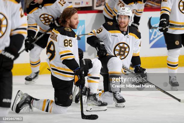 David Pastrnak and Matt Grzelcyk of the Boston Bruins warm up prior to the game against the Colorado Avalanche at Ball Arena on December 7, 2022 in...