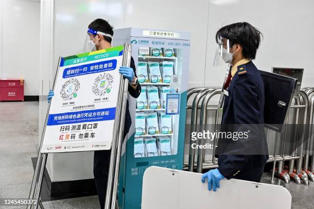 This photo taken on December 7, 2022 shows a subway staff member removing a poster for a Covid-19 health code used on entering the subway in...