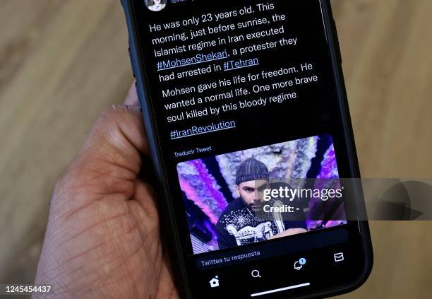 Person in the Cypriot capital Nicosia, checks a mobile phone on December 8 displaying a Tweet about the hanging by Iranian authorities of Mohsen...