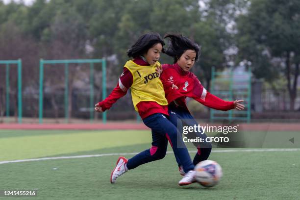 Members of a primary school girls' soccer team practice basic soccer skills and skills at the school's track and field in Hefei, Anhui Province,...