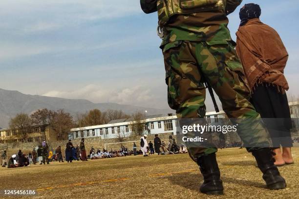 Taliban security personnel keep watch ahead of the court flogging of women and men at a football stadium in Charikar city of Parwan province on...