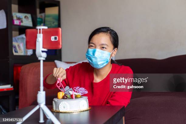 young asian girl doing teleconference birthday celebration with cake cutting ceremony - virtual ceremony stock pictures, royalty-free photos & images
