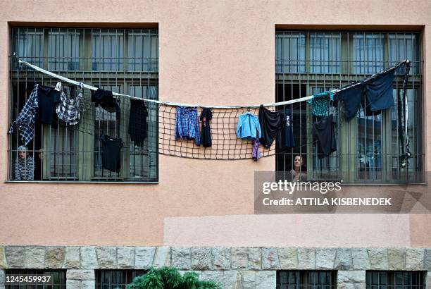 Teachers look out of the barred window of a secondary school in downtown Budapest on December 8 while checkered t-shirts - the symbol of the teachers...