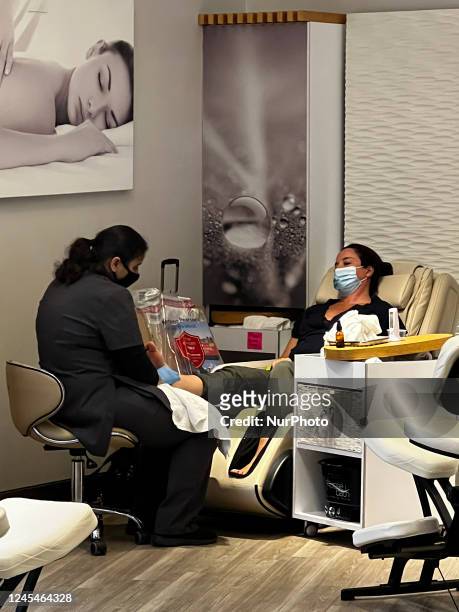 Passenger wearing a face mask enjoys a pedicure and foot massage at an airport spa while waiting for her flight during the COVID-19 pandemic at...