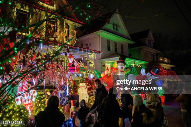 People look at homes decorated with Christmas lights and ornaments in the Dyker Heights neighborhood of New York City on December 8, 2022.