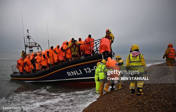 Migrants, picked up at sea attempting to cross the English Channel, are helped ashore from an Royal National Lifeboat Institution lifeboat, at...