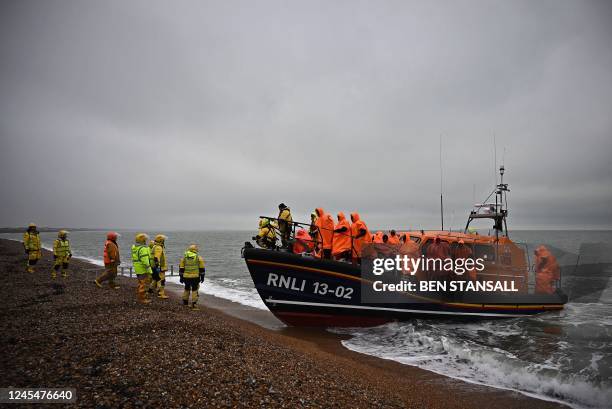 Migrants, picked up at sea attempting to cross the English Channel, wait to be helped ashore from an Royal National Lifeboat Institution lifeboat, at...