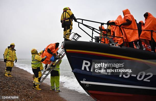 Migrants, picked up at sea attempting to cross the English Channel, are helped ashore from an Royal National Lifeboat Institution lifeboat, at...