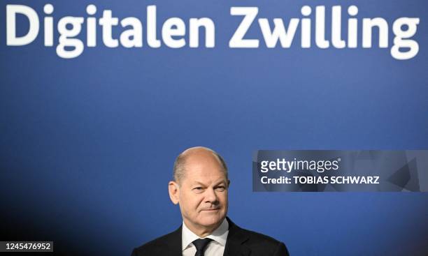 German Chancellor Olaf Scholz stands under an inscription reading "Digital twin" as he attends the Digital Summit of the German government on...