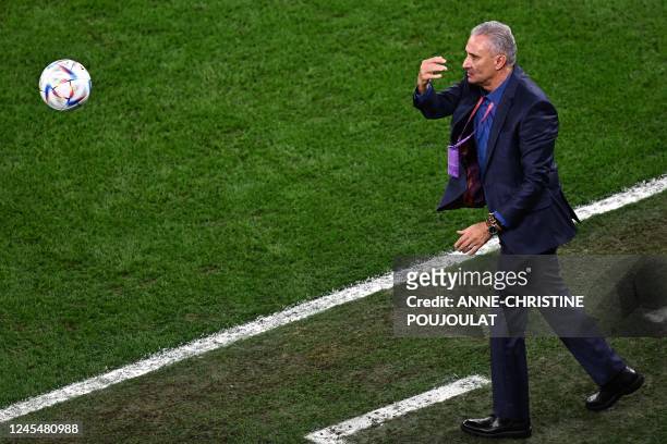 Brazil's coach Tite throws back the ball on the pitch during the Qatar 2022 World Cup quarter-final football match between Croatia and Brazil at...