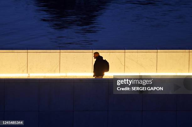 Man walks across a bridge in downtown Oslo, on late December 9, 2022.