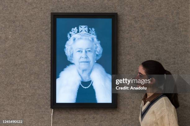 Staff member looks at 'Queen Elizabeth II ' lenticular 3D print on light box by Chris Levine, estimate: Â£45,000-60,000 during a photo call for...