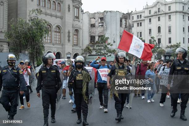 Riot police officers stand guard as supporters of Pedro Castillo, Peru's former president, protest his impeachment and arrest at Plaza San Martin in...