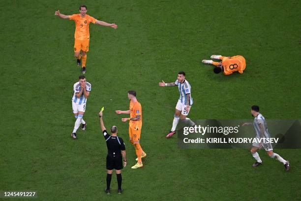 Argentina's defender German Pezzella receives a yellow card from Spanish referee Antonio Mateu during the Qatar 2022 World Cup quarter-final football...