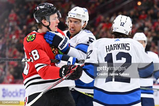 Brenden Dillon of the Winnipeg Jets comes to the defense of teammate Jansen Harkins as Harkins scuffles with MacKenzie Entwistle of the Chicago...