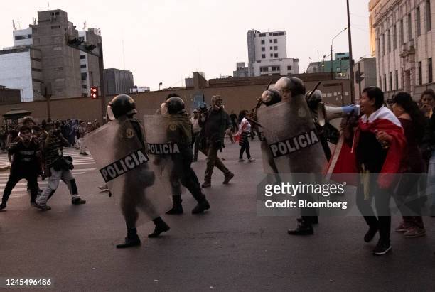 Riot police officers move towards supporters of Pedro Castillo, Peru's former president, as they protest his impeachment and arrest on Avenida...
