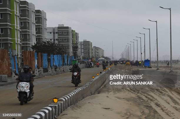 Motorist ride along a road covered in sand in Chennai on December 10 following the cyclonic storm Mandous.
