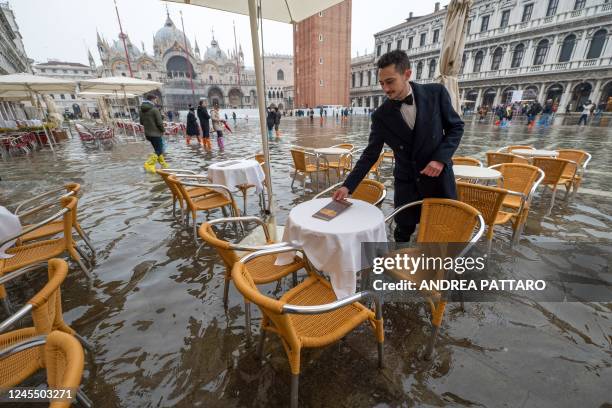 Waiter sets up tables on a flooded St. Mark's square in Venice on December 10 following an "Alta Acqua" high tide event, too low to operate the MOSE...