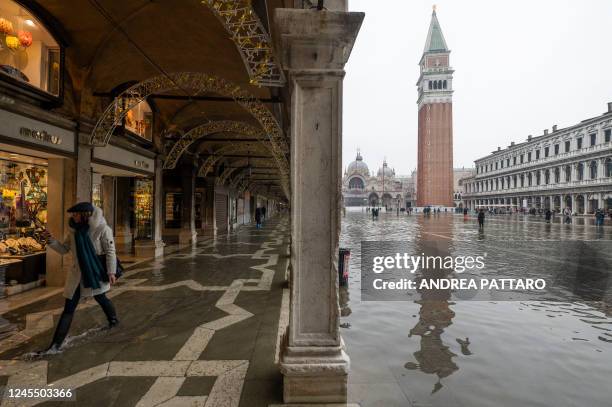 Woman walks across a passage along a flooded St. Mark's square in Venice on December 10 following an "Alta Acqua" high tide event, too low to operate...