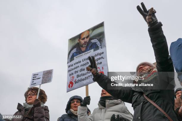 December 2022, Berlin: A woman holds a sign with Mohsen Shekari, recently executed in Iran, and the message "How many more innocent people have to...