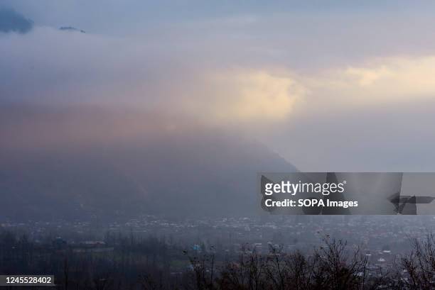 Sunrays pass through clouds covered mountain during a cold evening after a rainfall in the outskirts of Srinagar.