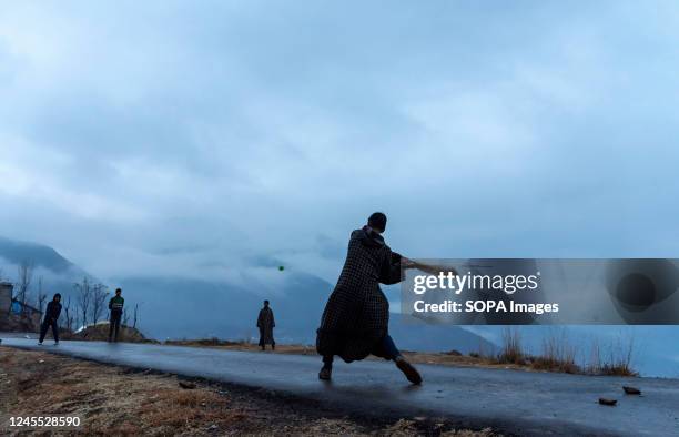 Kashmiri kids play cricket on a mountain during a cold evening after rainfall in the outskirts of Srinagar.