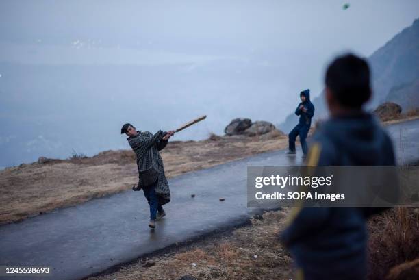 Kashmiri kids play cricket on a mountain during a cold evening after rainfall in the outskirts of Srinagar.