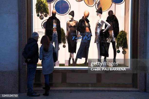 Couple look at mannequins in a shop window in a shopping street in Barcelona on December 10 ahead of Christmas holidays