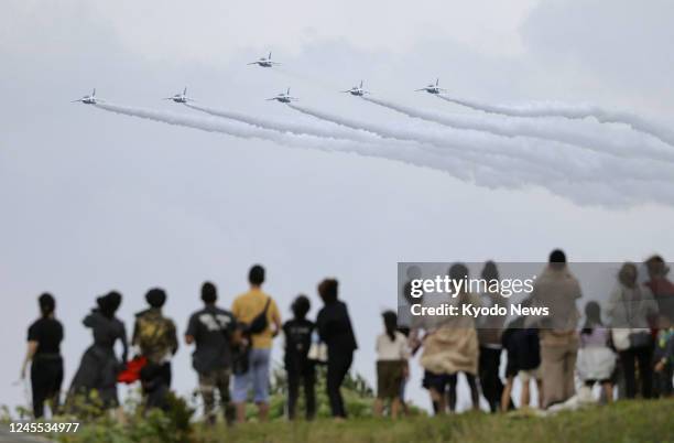 People watch the Japan Air Self-Defense Force's Blue Impulse aerobatic team fly over Miyako island in Okinawa Prefecture, southern Japan, on Dec. 11...