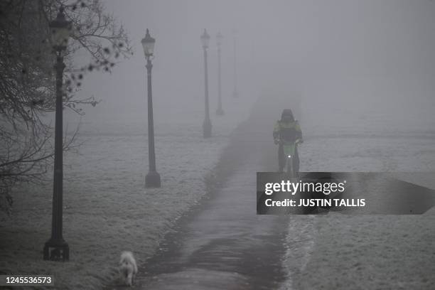 Cyclist makes their way through fog on a frosty morning at Primrose Hill, in north London, on December 11, 2022. - Areas of the UK are experiencing...