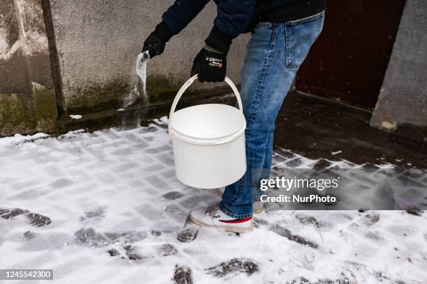 Man sprinkles a sidewalk with salt after snowfall in the city as Arctic blast heads for Europe. Krakow, Poland on December 11, 2022.