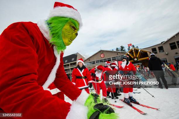 Person dressed as the Grinch stands out among the hundreds of Santa Clauses during the Santa Sunday event at Sunday River Resort in Newry, Maine on...