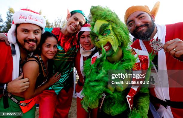 Runner dressed as The Grinch poses for a picture with other runners dressed as Santa Claus during the the annual "Run Santa Run" Christmas race in...
