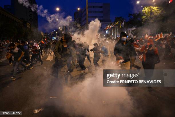 Supporters of former President Pedro Castillo take cover from tear gas thrown by the police during clashes on a demonstration demanding his release...