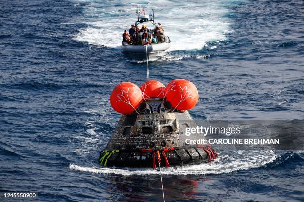 Navy divers attach winch cables to NASAs Orion capsule after being successfully secured by NASA and US Navy teams off the coast of Baja California,...