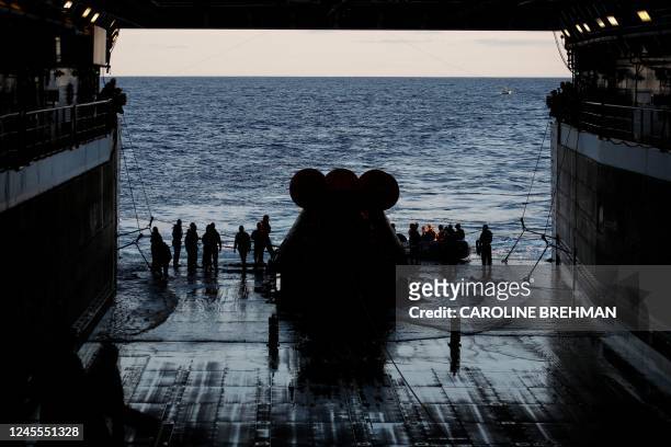 Members of the US Navy dive team return to the well deck after successfully securing NASAs Orion capsule on the USS Portland off the coast of Baja...